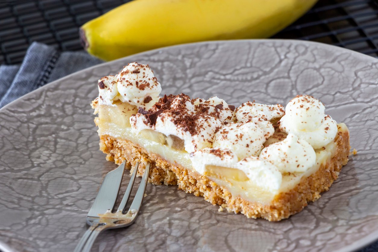 Piece of Banoffee pie with banana, chocolate, caramel and whipped cream. Selective focus.