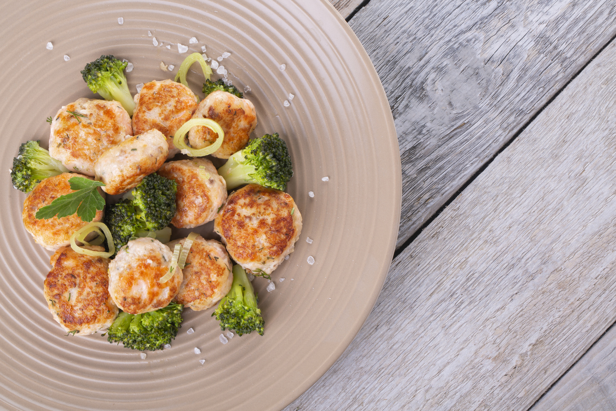 Plate of salmon meatballs with vegetables on a wooden table